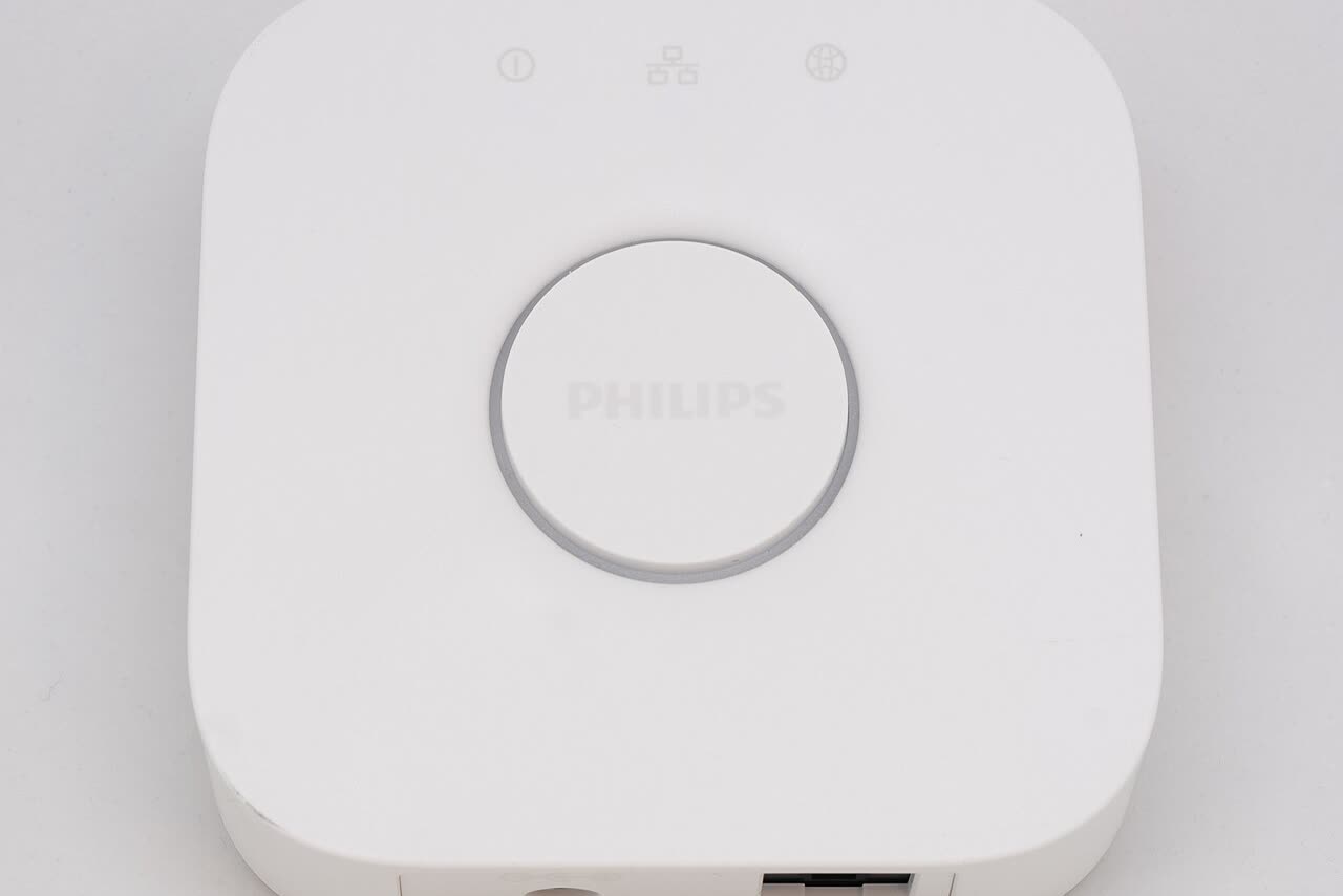 A Philips Hue Bridge hub with network cable on a wooden surface