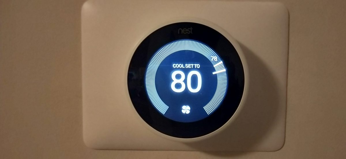 Google Nest smart thermostat mounted on a living room wall