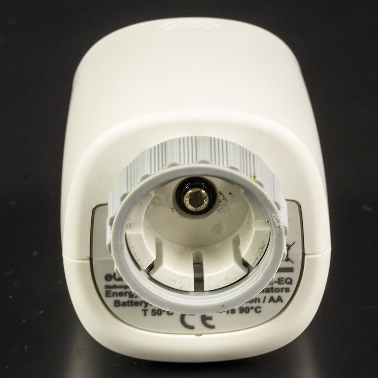 Underside of a modern smart radiator thermostat showing the threaded valve fitting